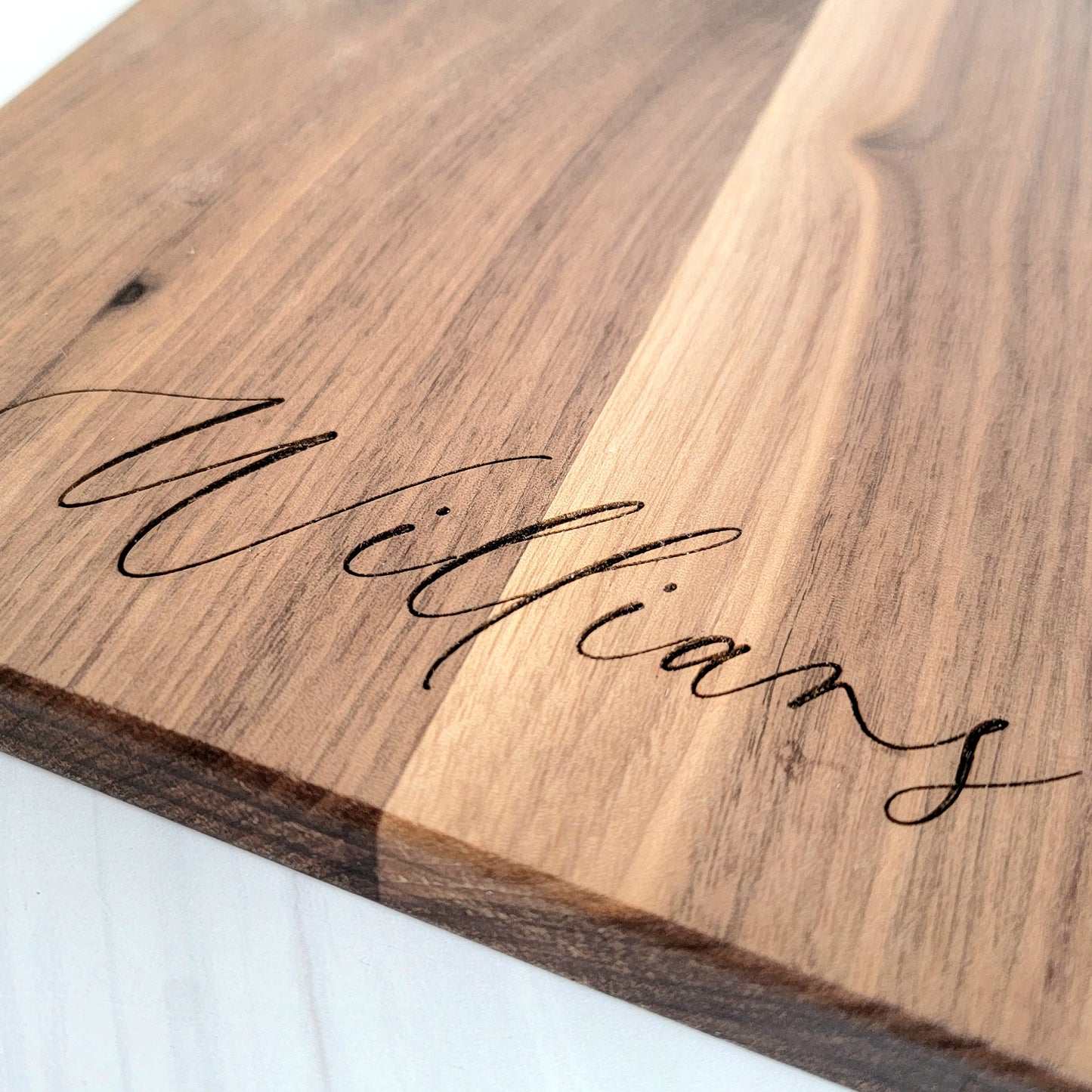 Elegant walnut cutting board with rich wood grain, showcasing a smooth surface and rounded edges. Size is 17 X 8.75. You have 6 available options to choose from for engraving. 